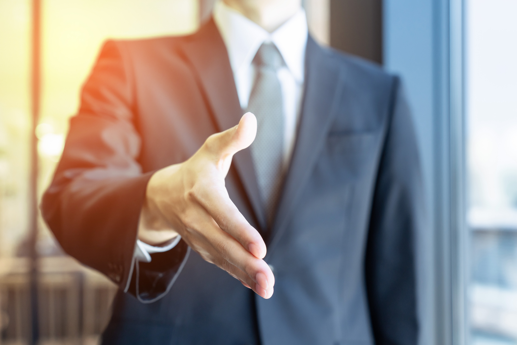 スーツの男性が握手を求めている画像